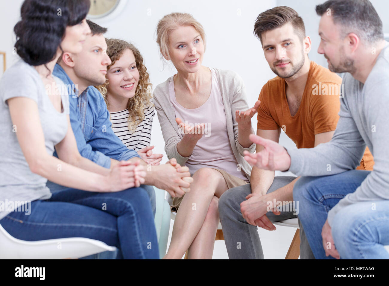 Group of people sitting in a circle, showing support to a man fighting alcohol addiction Stock Photo