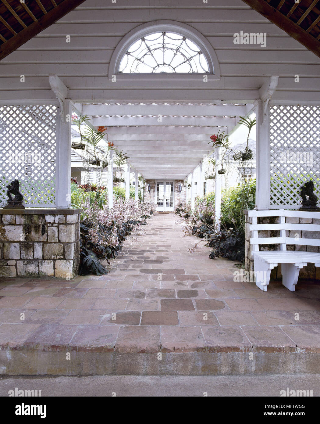An exterior Jamaican weather board house with stone paved walkway