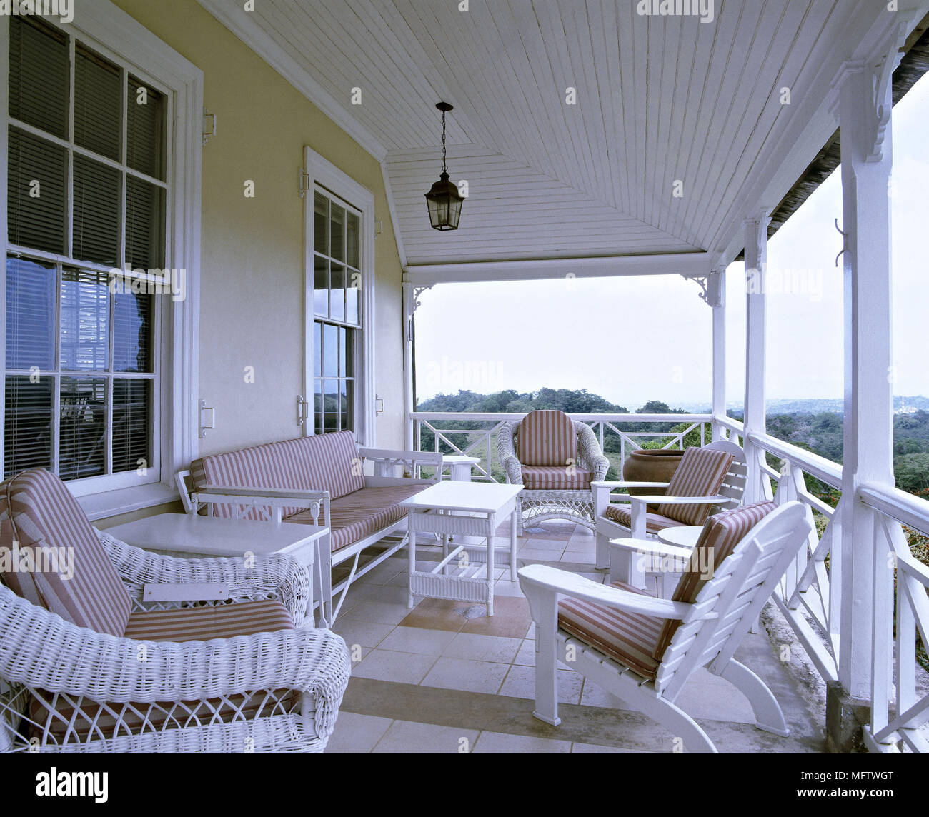 An exterior Jamaican weather board house with veranda white wicker