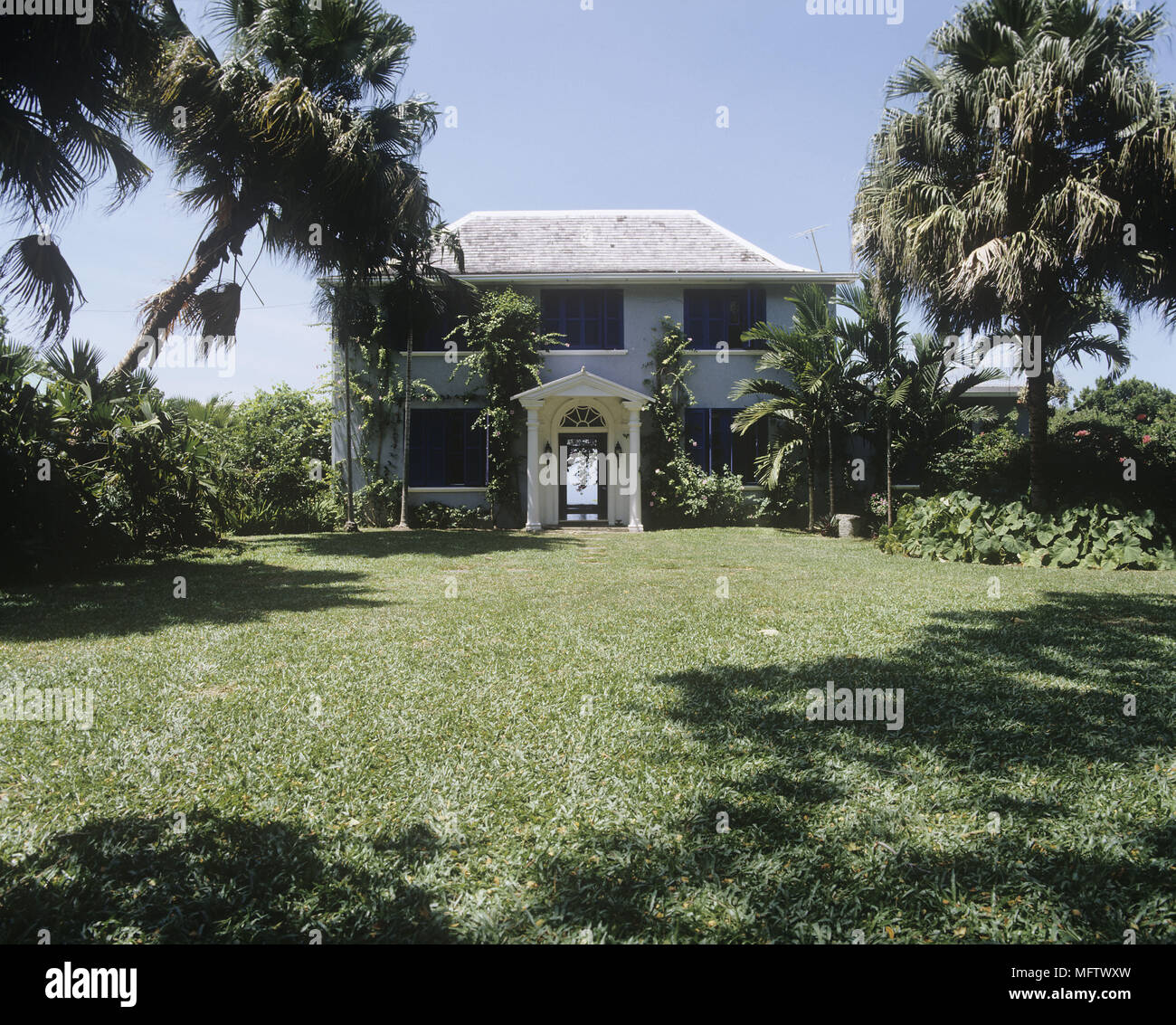 Exterior shot of country house in Jamaica with grass lawn and palm