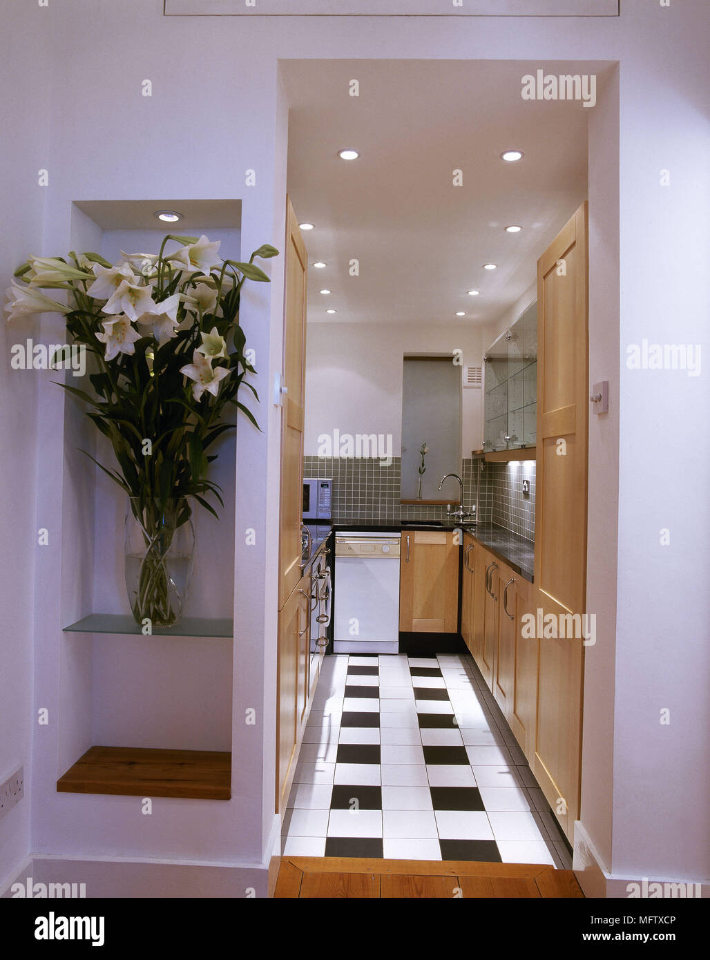 White galley kitchen with wood units and black and white tiled floor Stock Photo - Alamy
