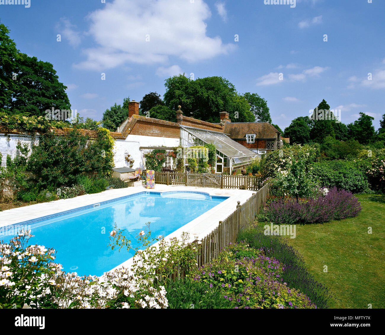A country garden with an outdoor swimming pool, shrubs and flower ...