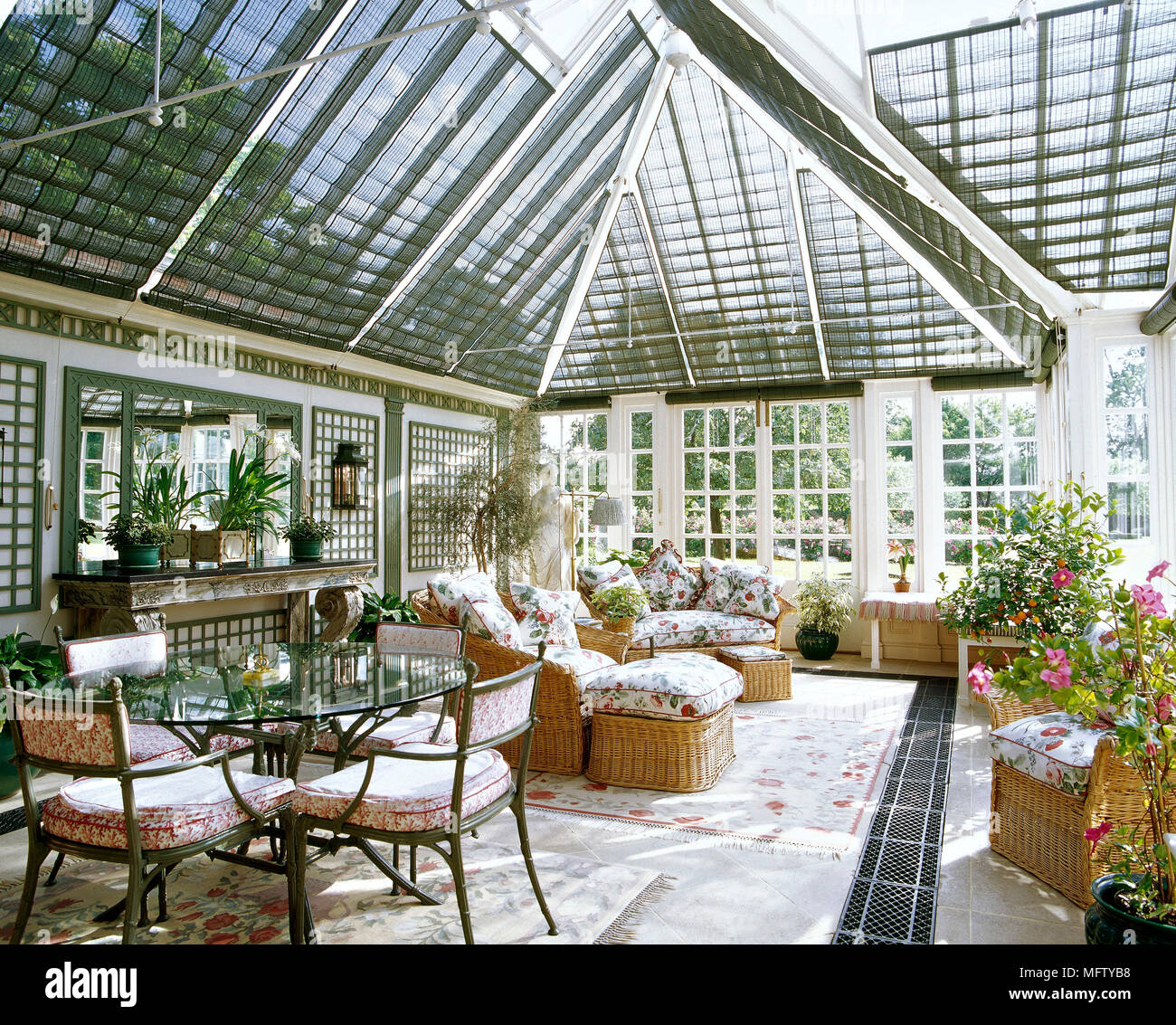 A traditional conservatory with wicker furniture, glass dining table, metal chairs, Stock Photo