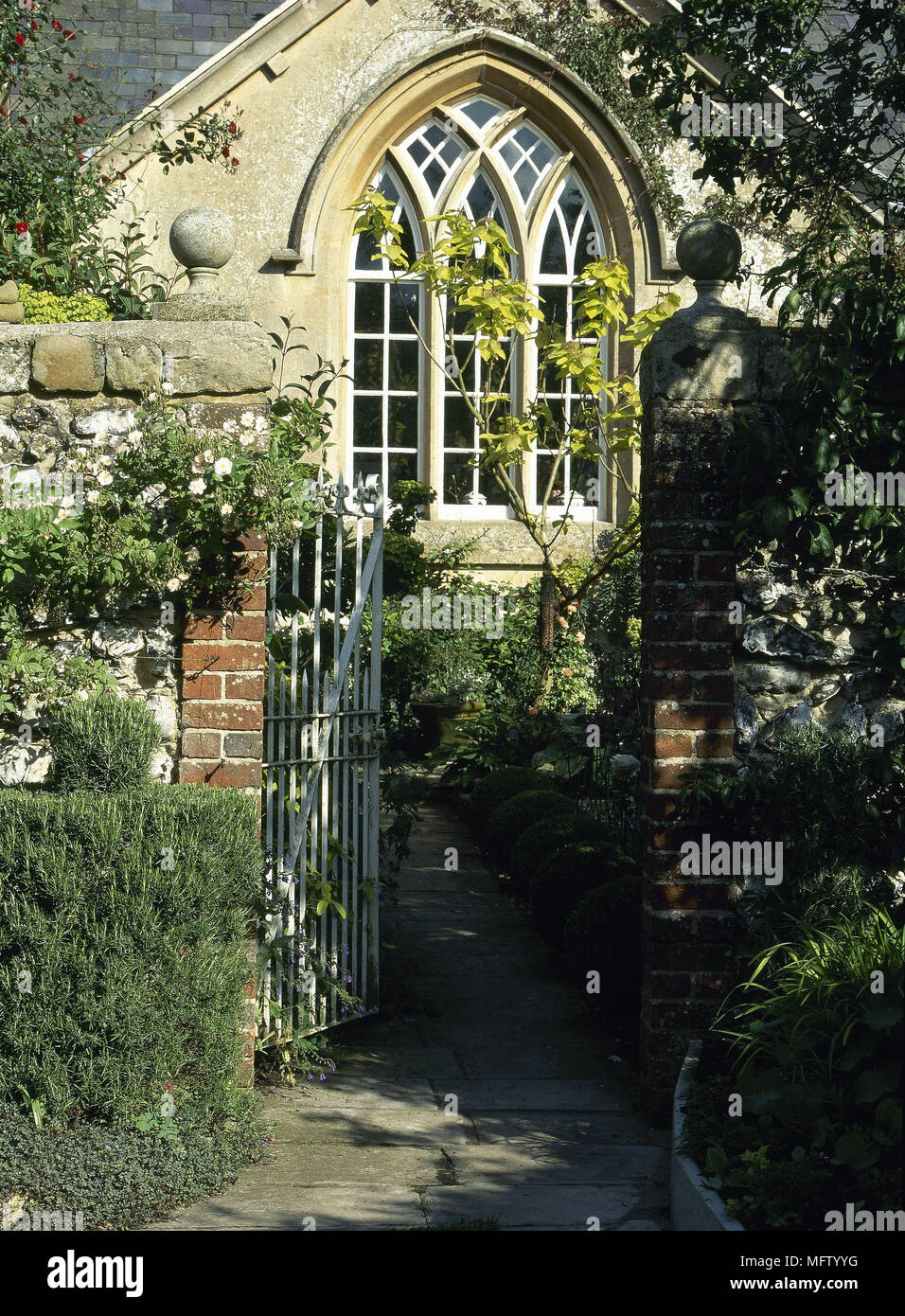 Wrought iron gate open leading to country style house with arched window Stock Photo