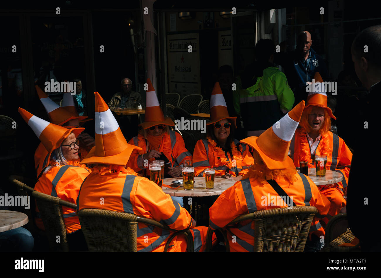 Amsterdam, Netherlands - 27 April, 2017: Group of people wearing orange costumes with hat like traffic cone on Day of the King in Amsterdam Stock Photo
