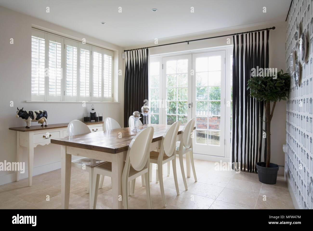 Wooden Dining Table And White Plastic Chairs In Room With Black Curtains Wooden Dining Table And White Plastic Chairs In Room With Black Curtains