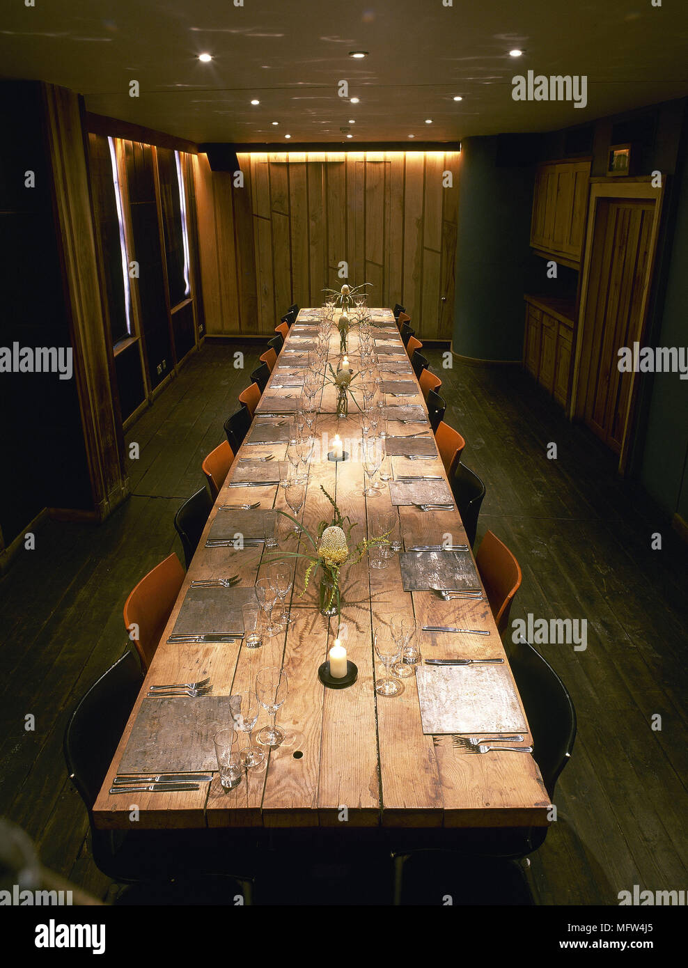 Dining room with long wooden table set for dinner. Stock Photo