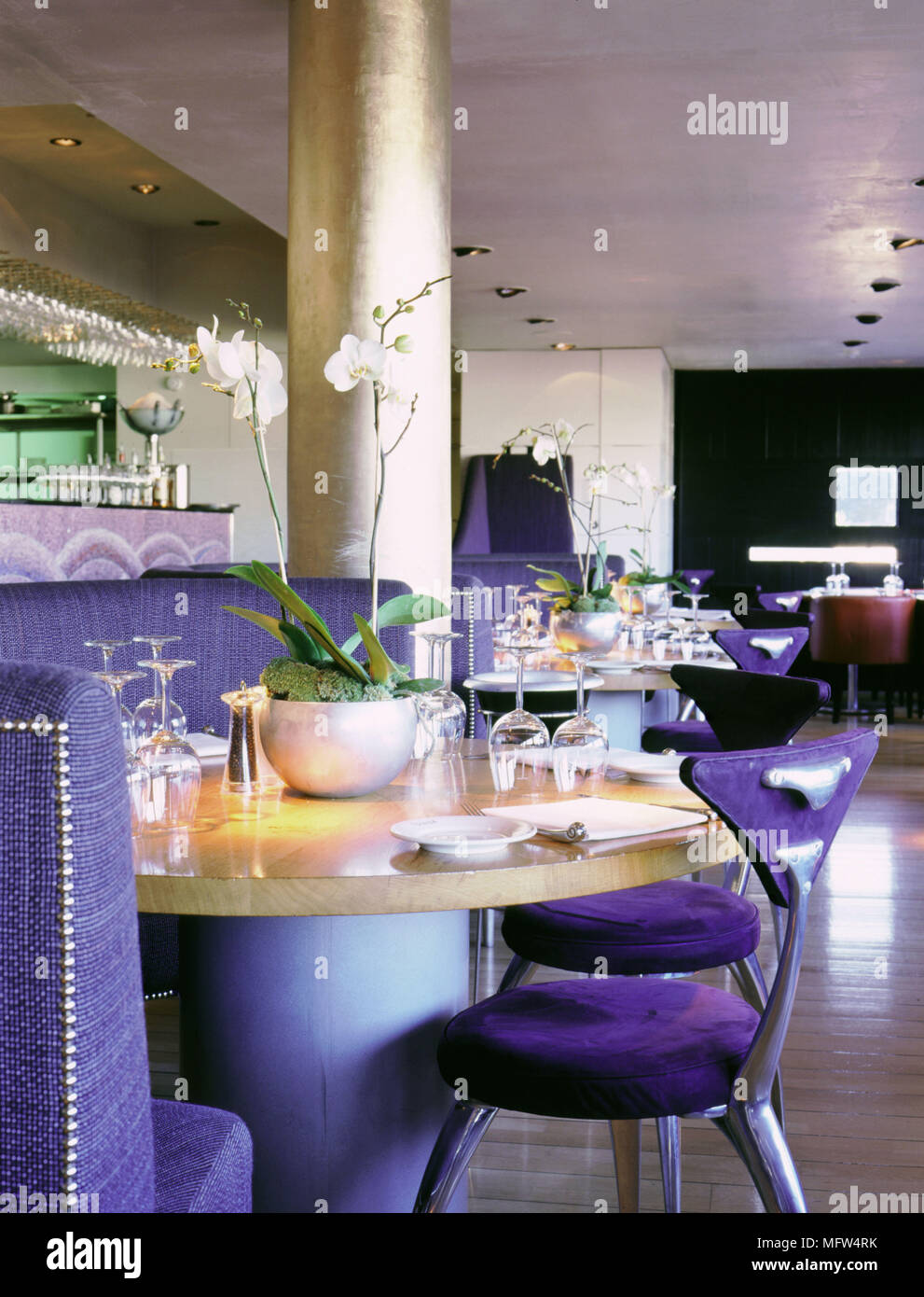 Interior of the Tower Restaurant with gilt dining tables table settings modern chairs and potted orchids. Stock Photo