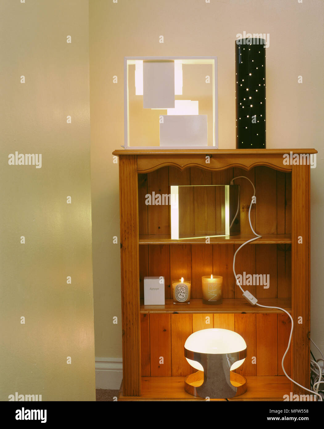 Pine bookshelf displaying modern sculptural lighting and lit candles