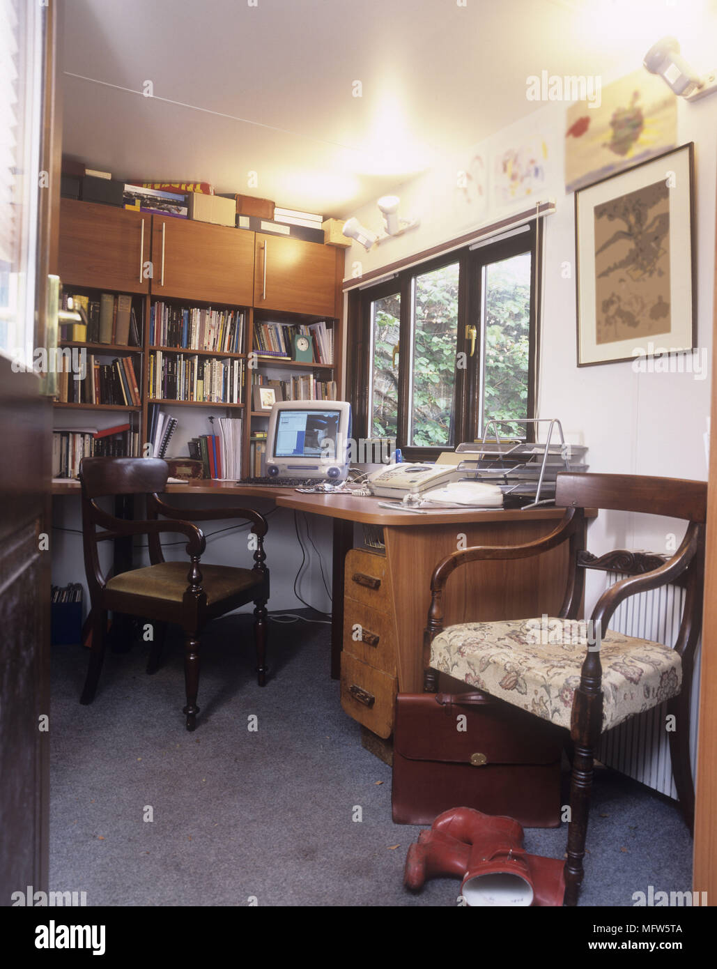 A traditional room with book shelves a desk and chairs and pictures on ...