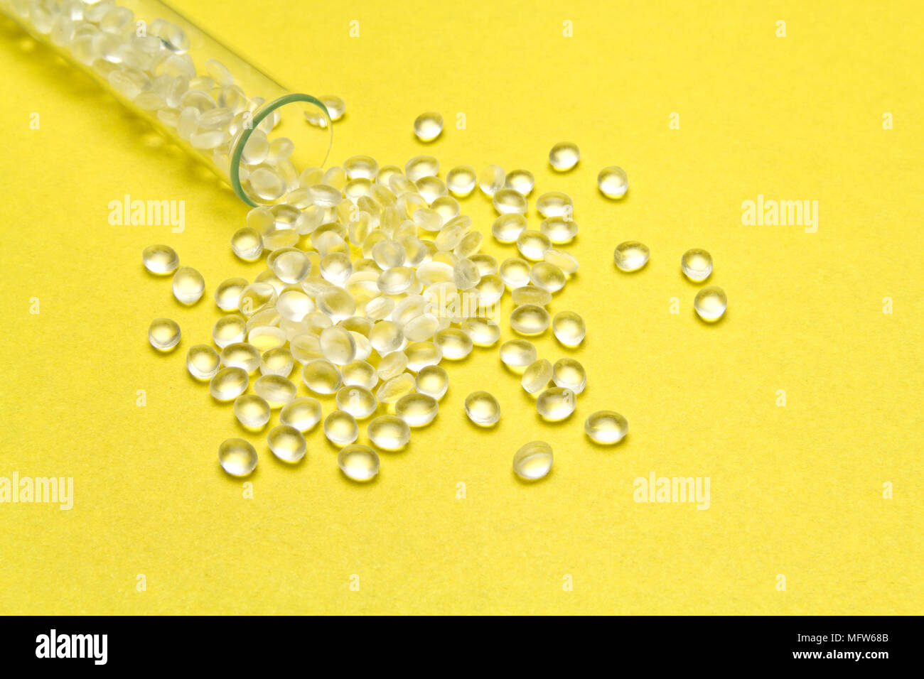 Transparent Polyethylene granules on a yellow background.HDPE Plastic pellets. Plastic Raw material . IDPE. Stock Photo