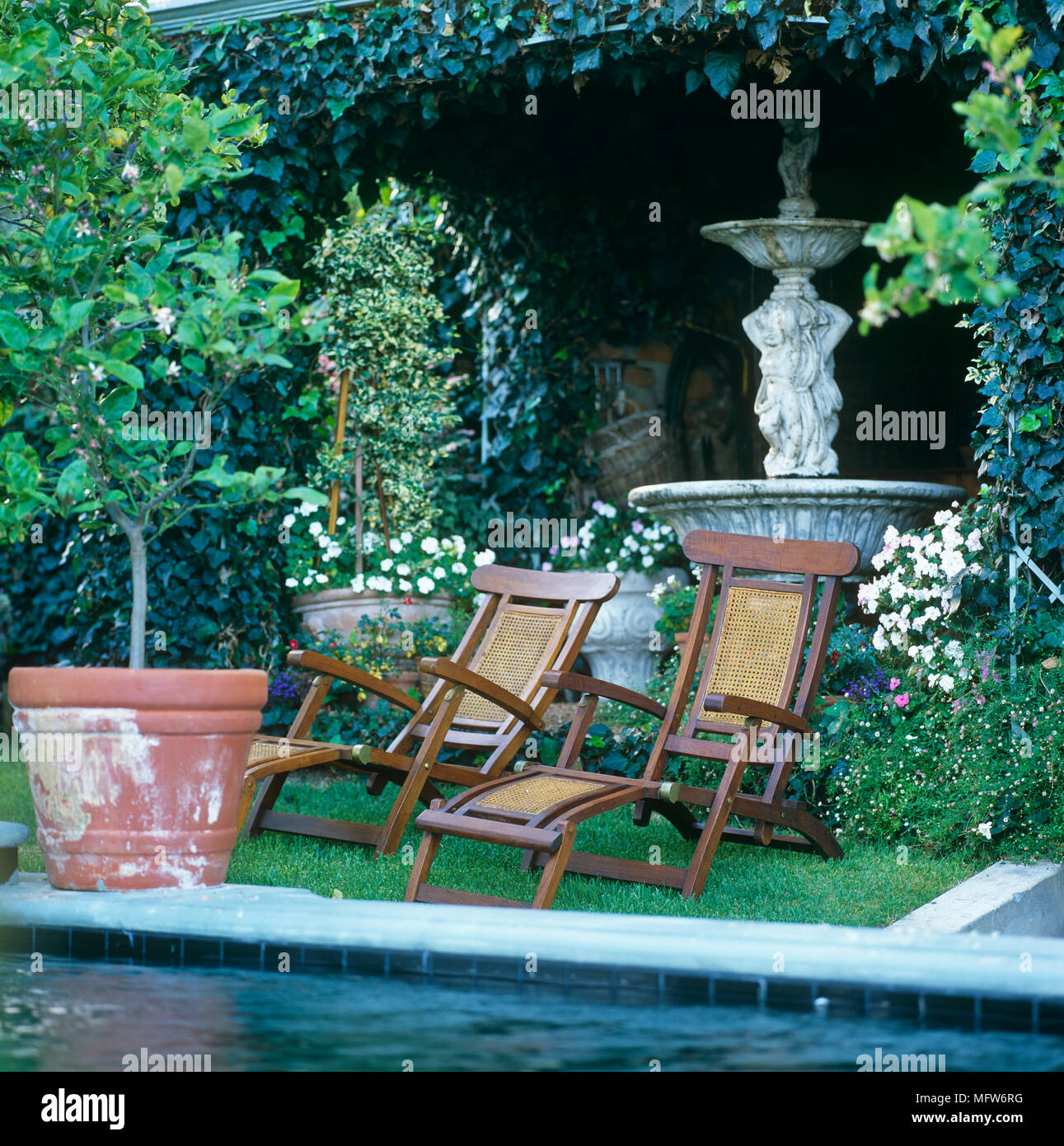 Two sun loungers by the edge of a swimming pool Stock Photo - Alamy