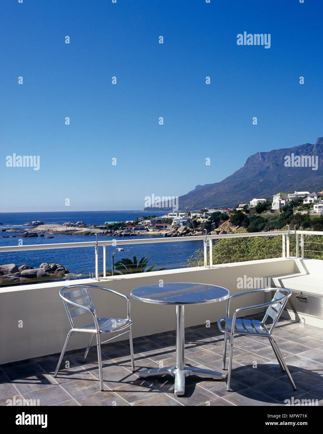 Metal table and chairs on tiled patio with view of Cape Town beaches ...