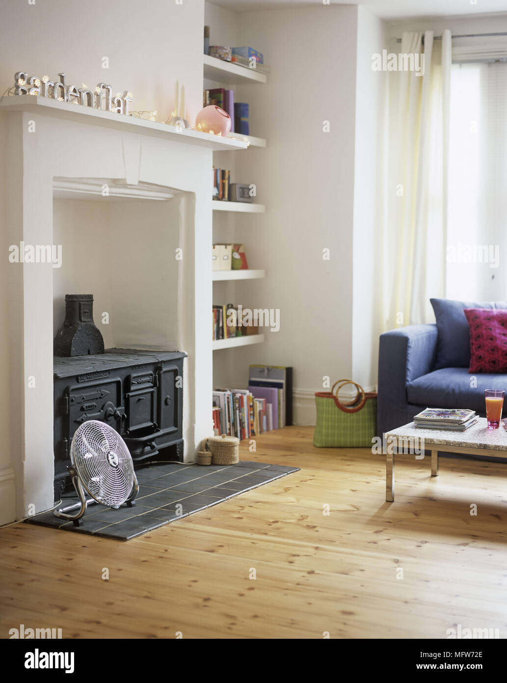 A detail of a modern white sitting room wood burning stove in fireplace