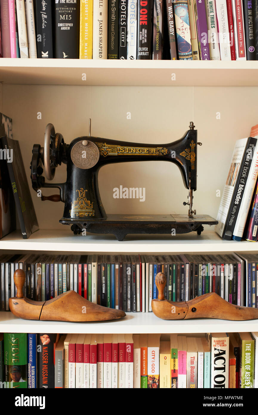 Old fashioned singer sewing machine on shelving with books Stock Photo