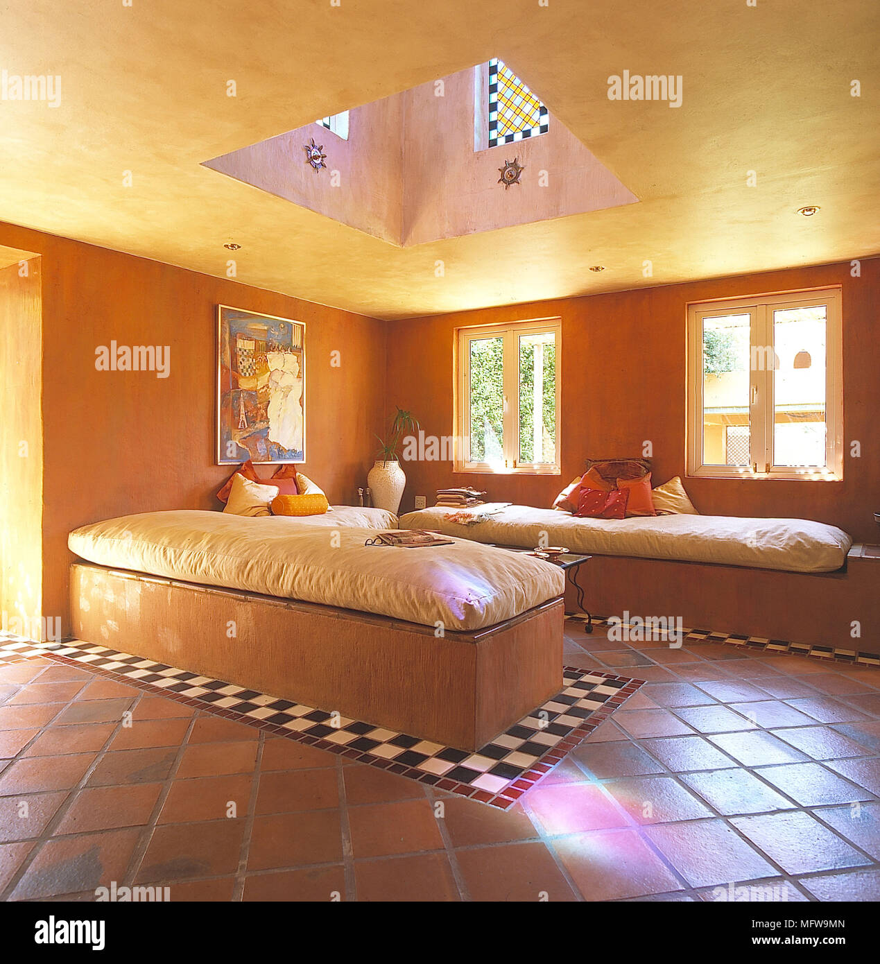 Wooden daybeds with cushions in orange and yellow room Stock Photo