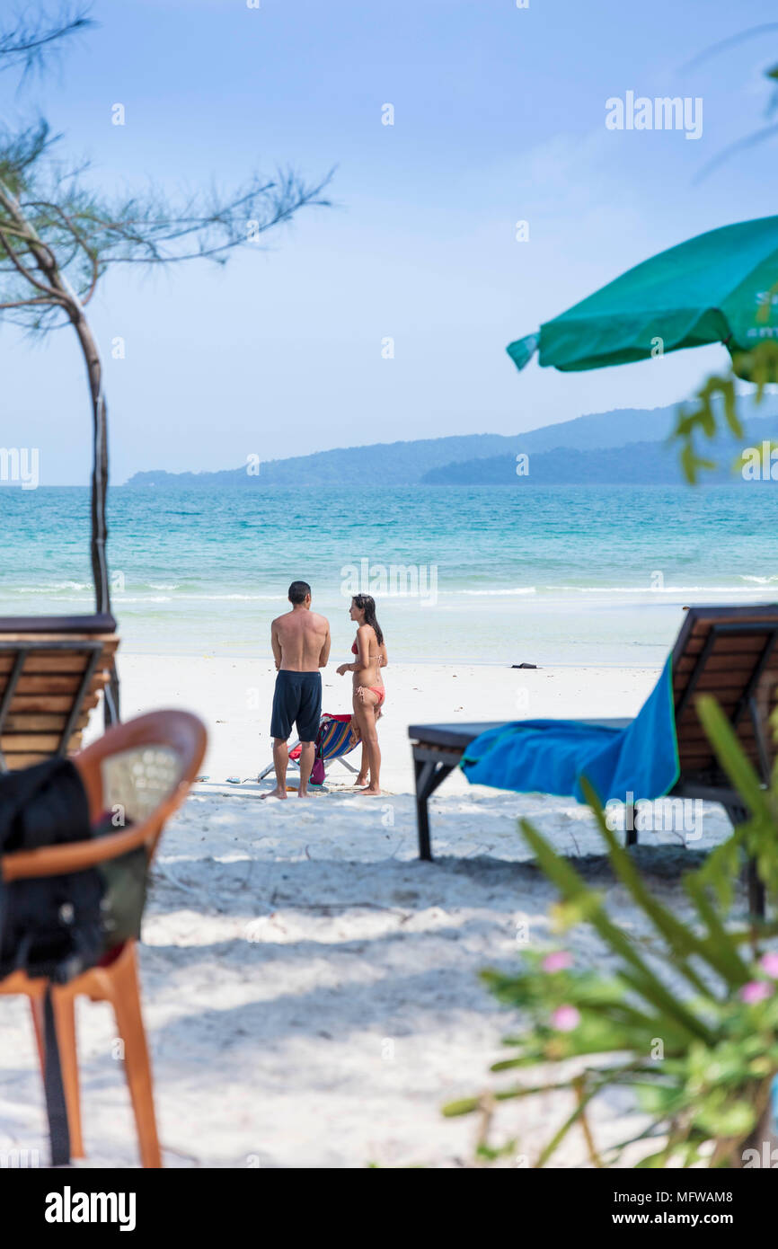 Candid shot of a young couple talking on a white sand beach on an island in Southeast Asia Stock Photo