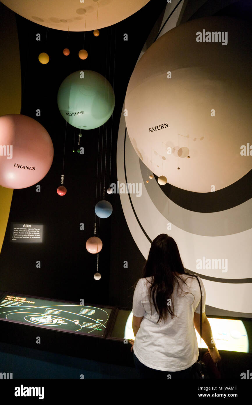 Young woman looking at a model of the planets and solar system, National Air & Space Museum, Smithsonian, Washington DC USA Stock Photo