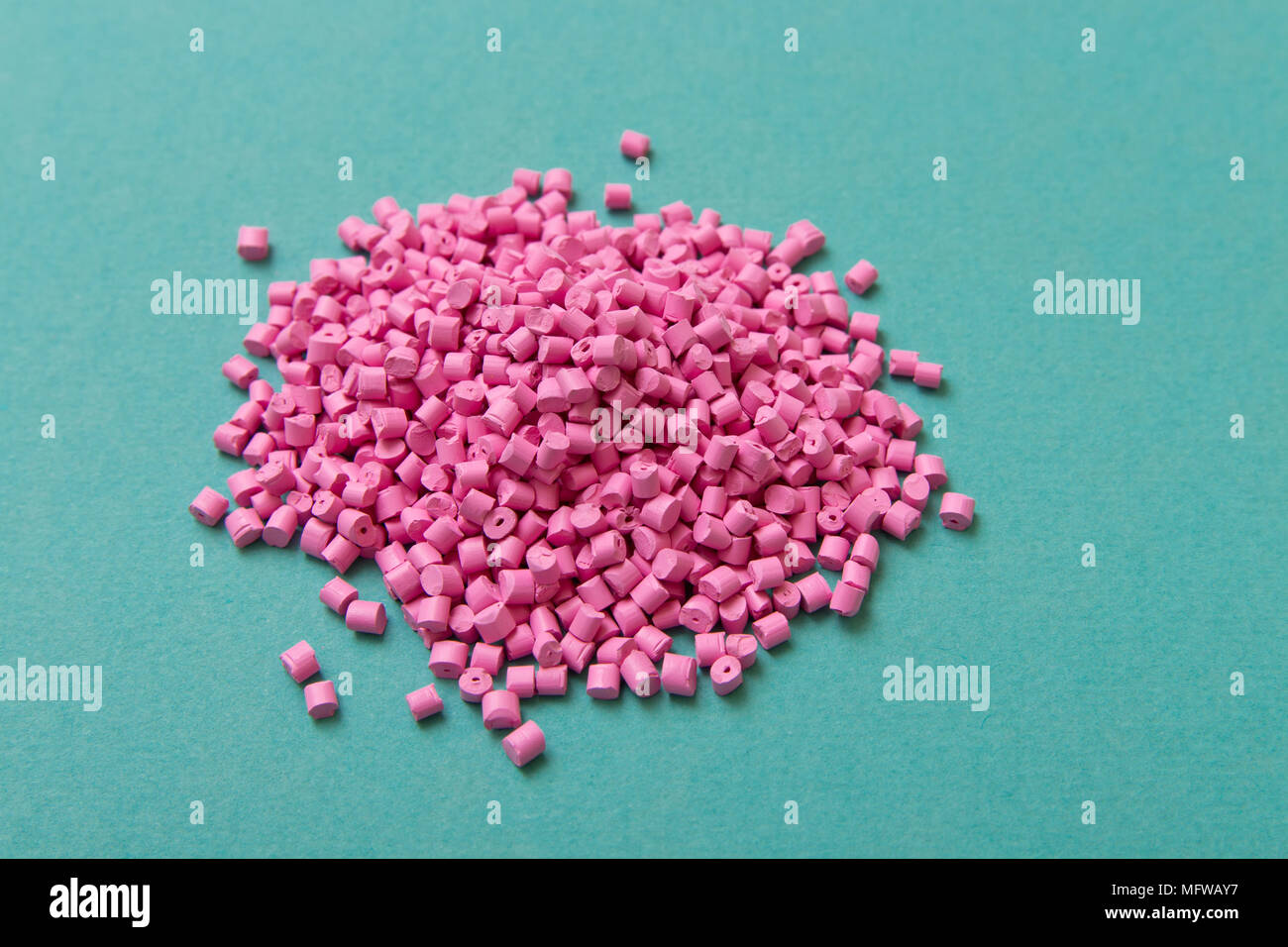 Plastic pellets. Pink Plastic granules on a turquoise background. Plastic Raw material . Stock Photo
