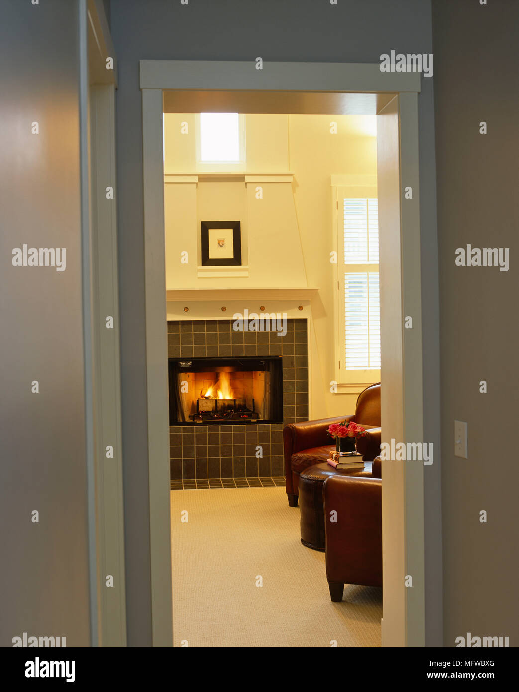 View through open door to leather armchairs in front of fireplace with