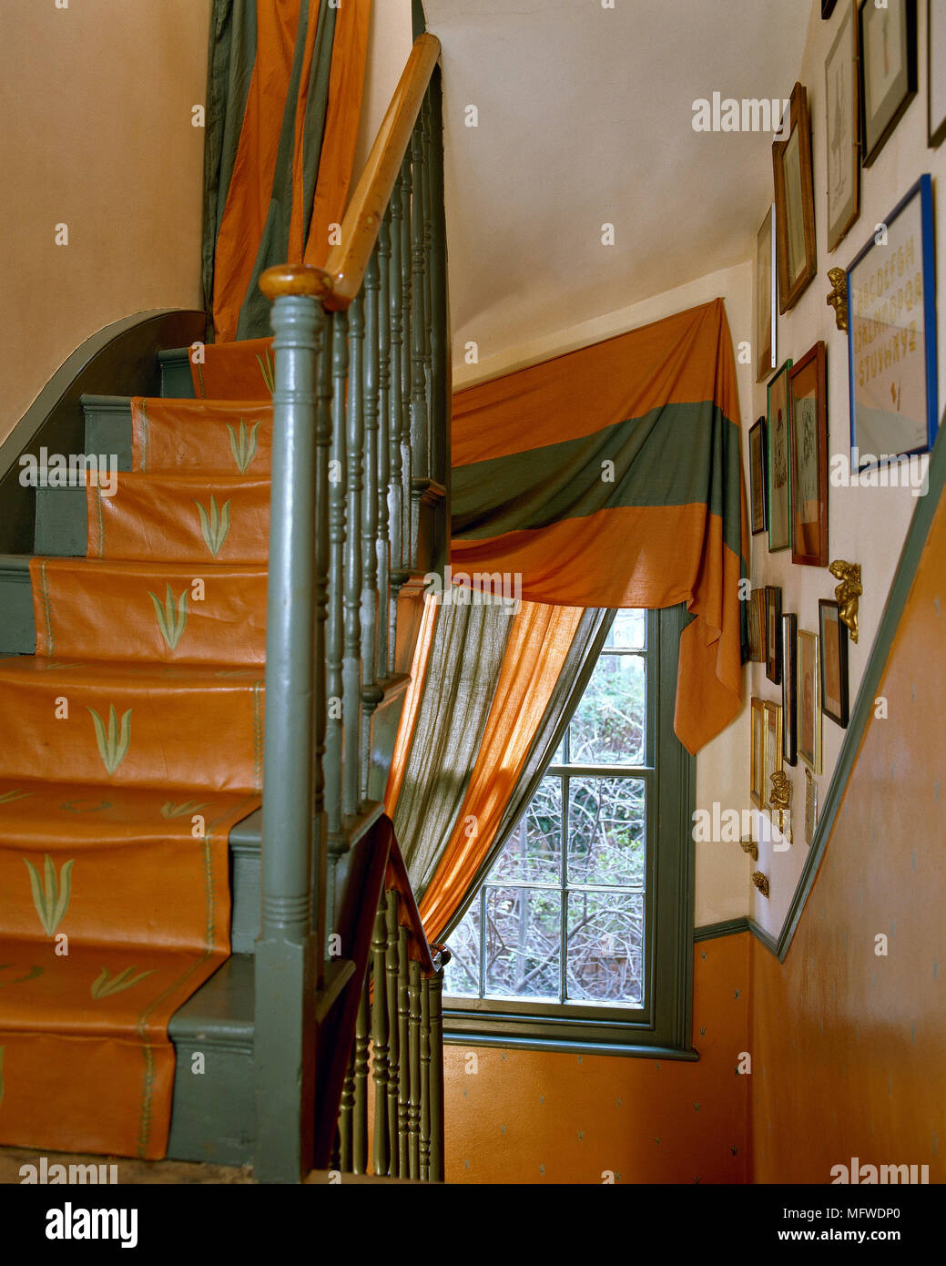 Terracotta hallway with staircase, window draped with red curtain Stock