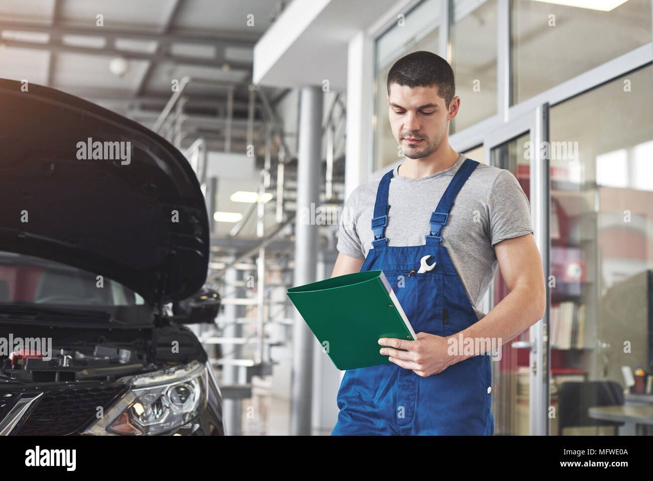 car service, repair, maintenance and people concept - auto mechanic man or smith with clipboard at workshop Stock Photo