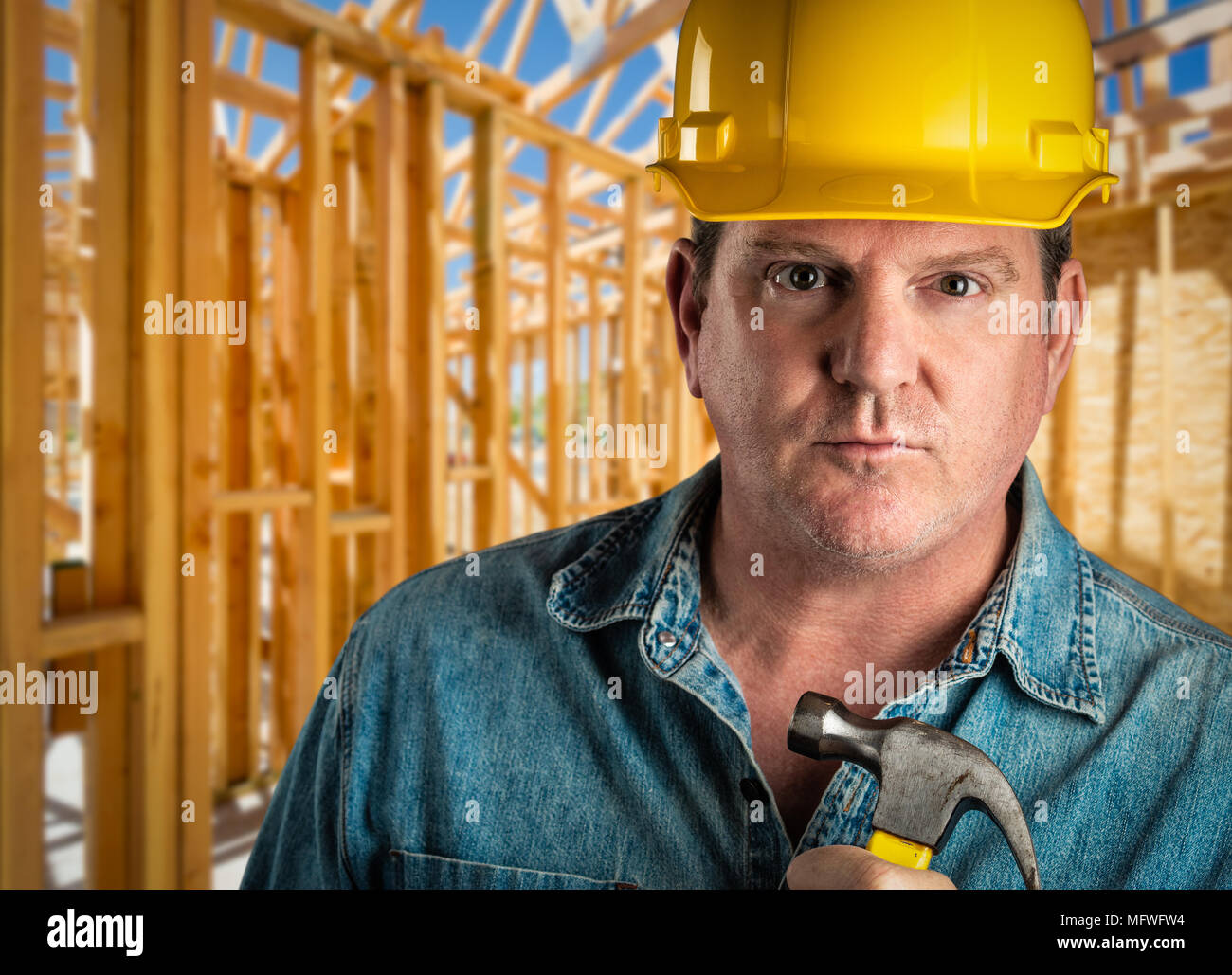 Serious Contractor in Hard Hat Holding Hammer At Construction Site