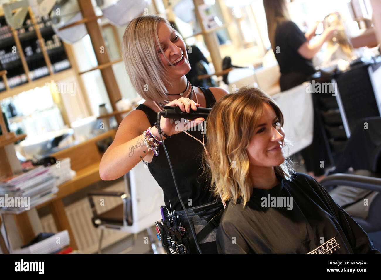 A hairdresser pictured attending to a young girls hair at a hairdressers in Chichester, West Sussex, UK. Stock Photo