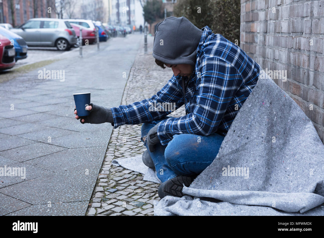 Beggar's Hand Wearing Gloves Holding Disposable Cup Stock Photo