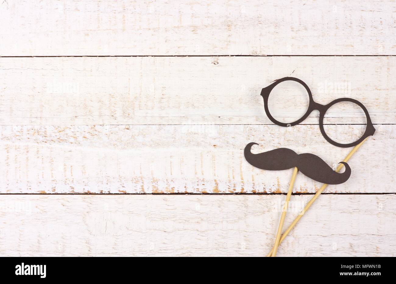 Funny mustache and glasses on sticks against a rustic white wood background. Top view with copy space. Stock Photo