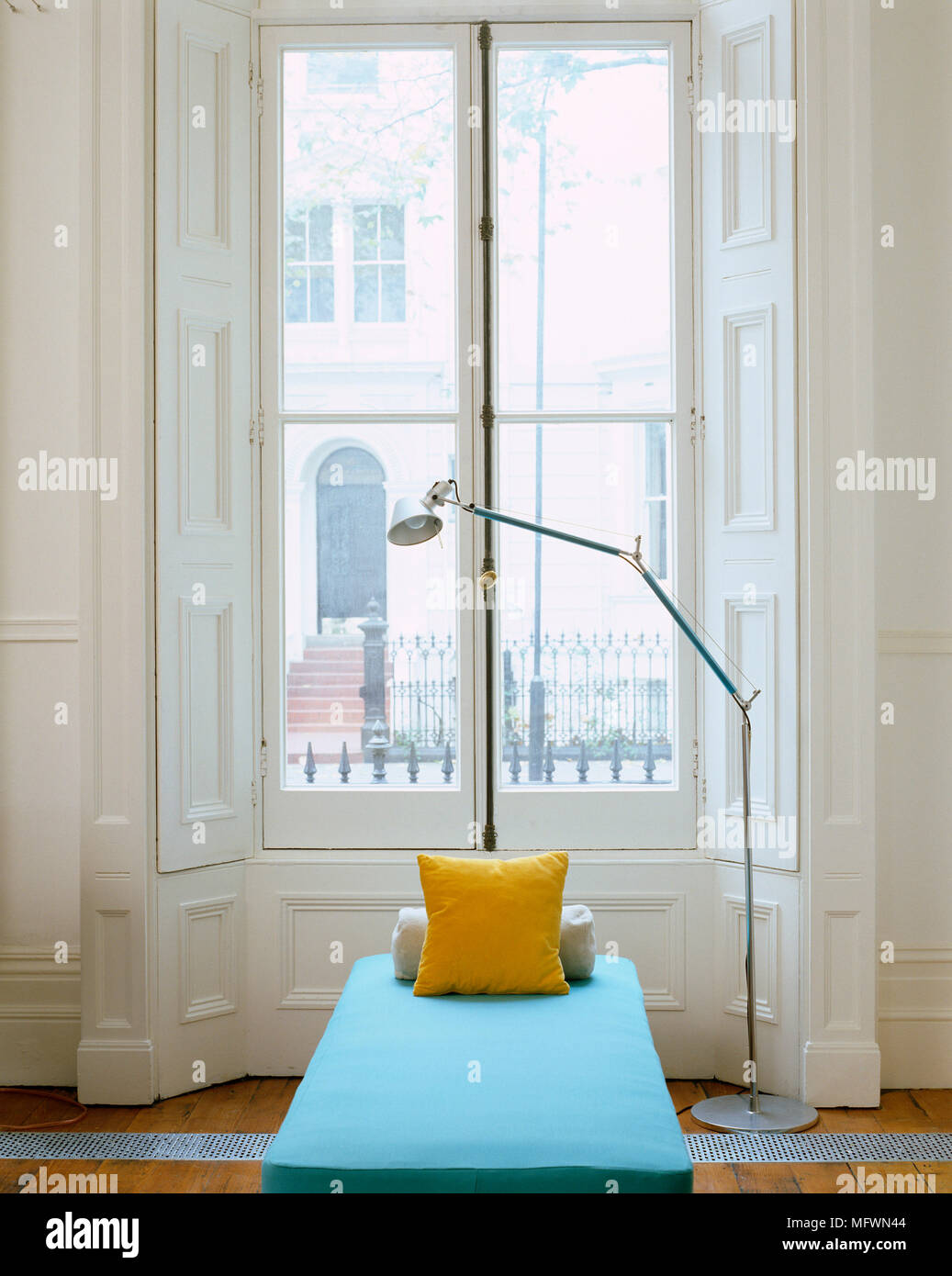 Floor lamp next to contemporary daybed set in period bay window Stock