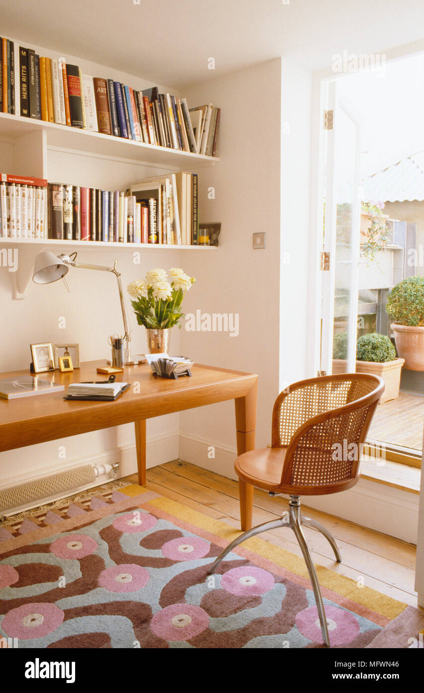 Wooden chair at desk with book shelves above in contemporary home office  Stock Photo - Alamy