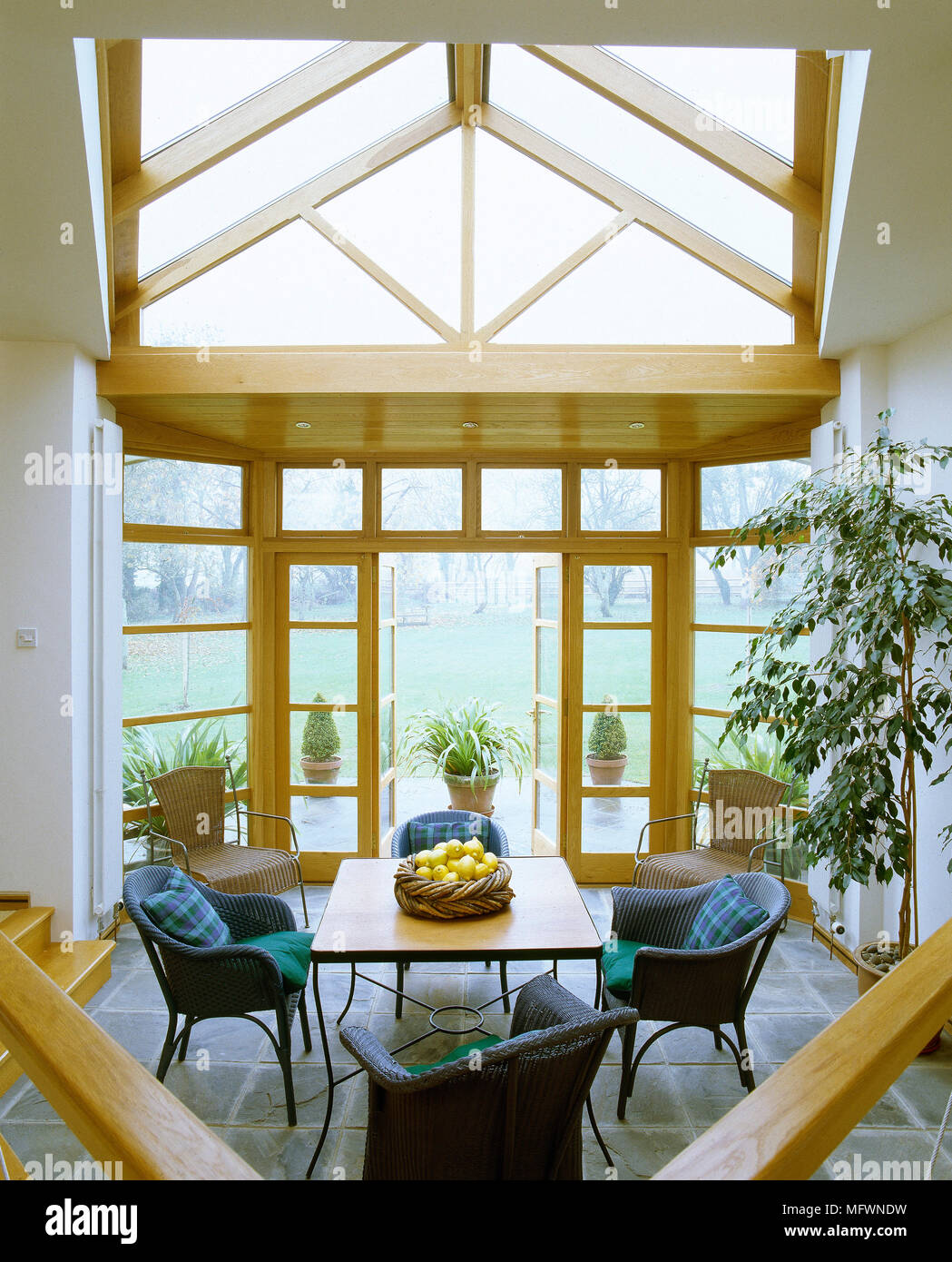A modern conservatory with a pitched glass roof, dining table with