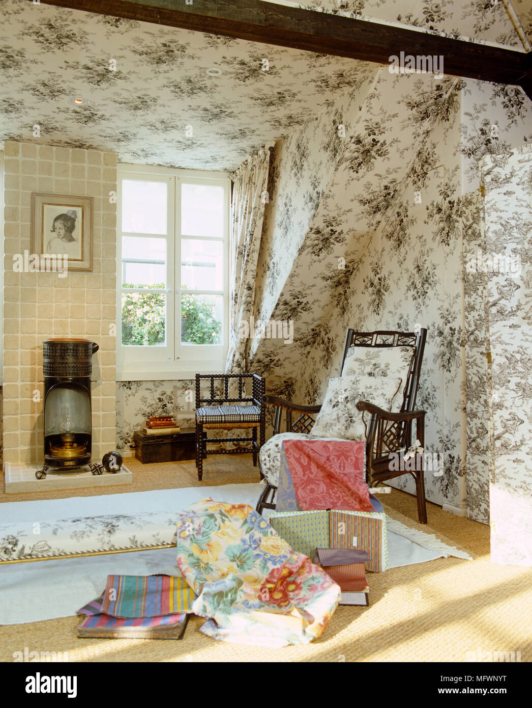 Fabrics in front of wooden chair in sitting room with toile de Jouy pattern wallpaper Stock Photo
