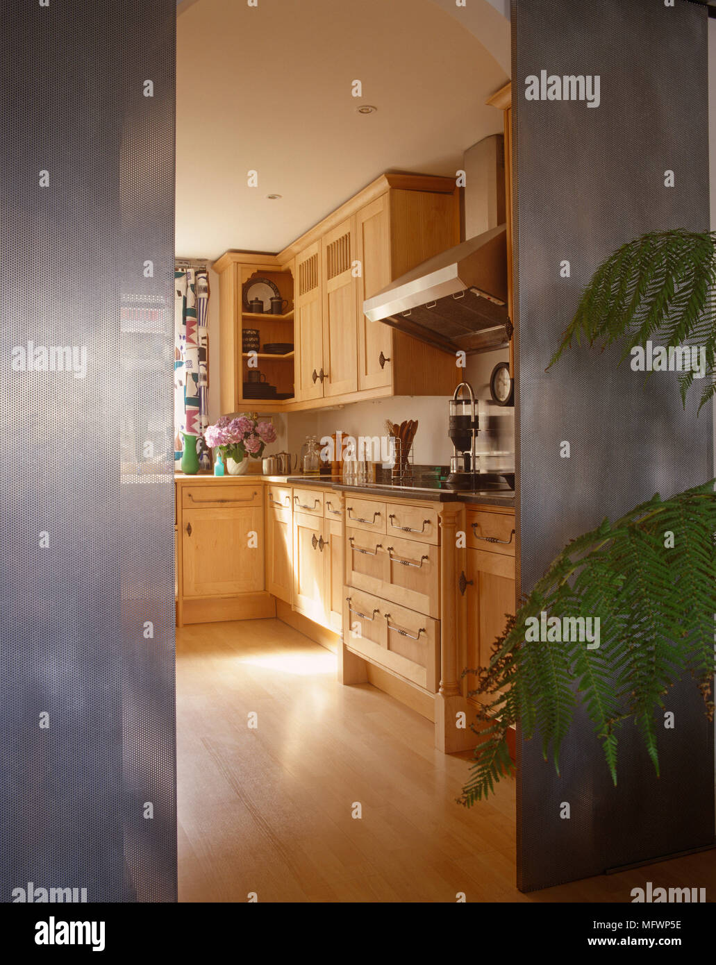 View of kitchen with wooden units through metal grate sliding doors
