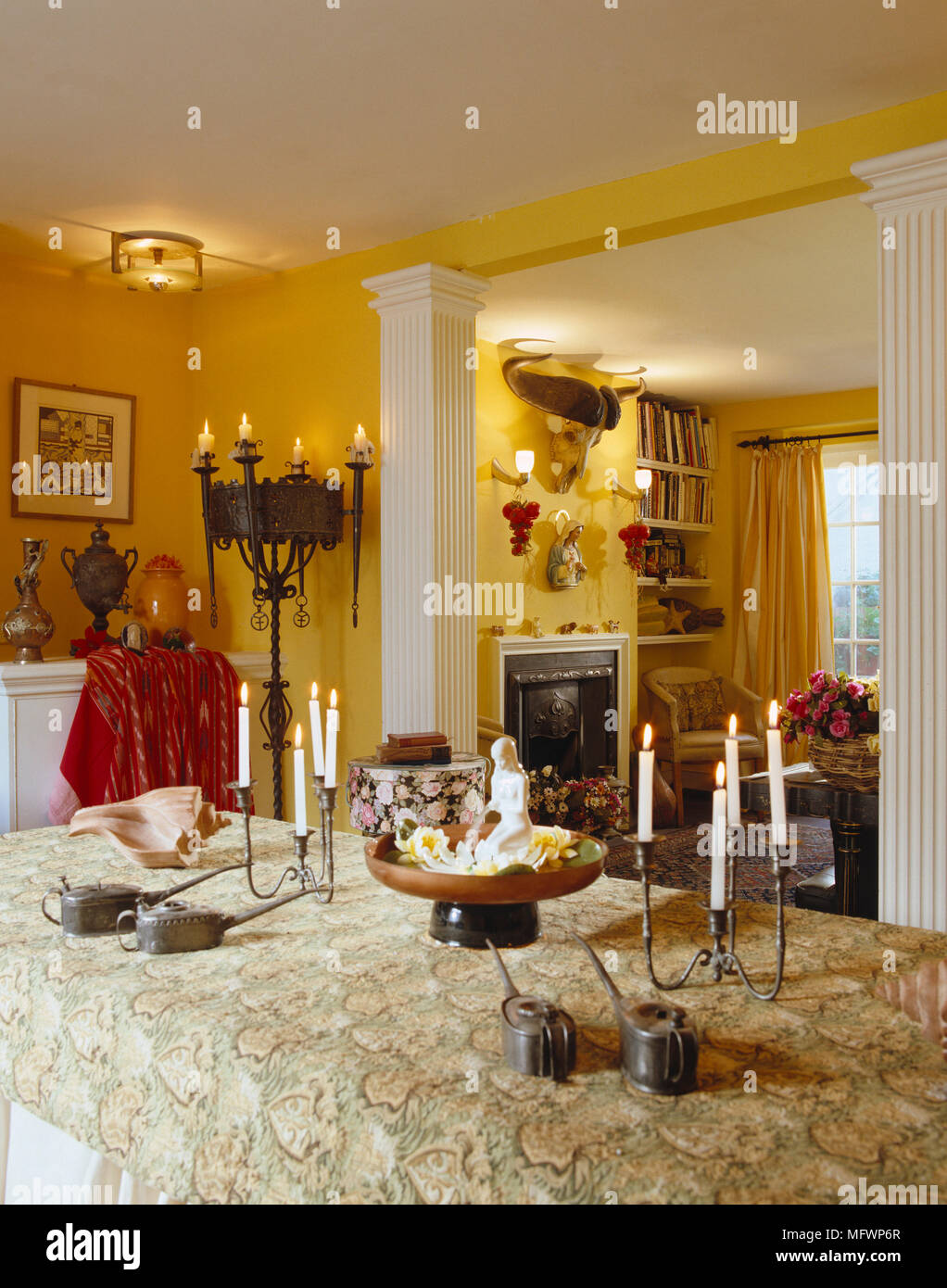 Wrought Iron Candelabra On Dining Table In Yellow Room Stock Photo