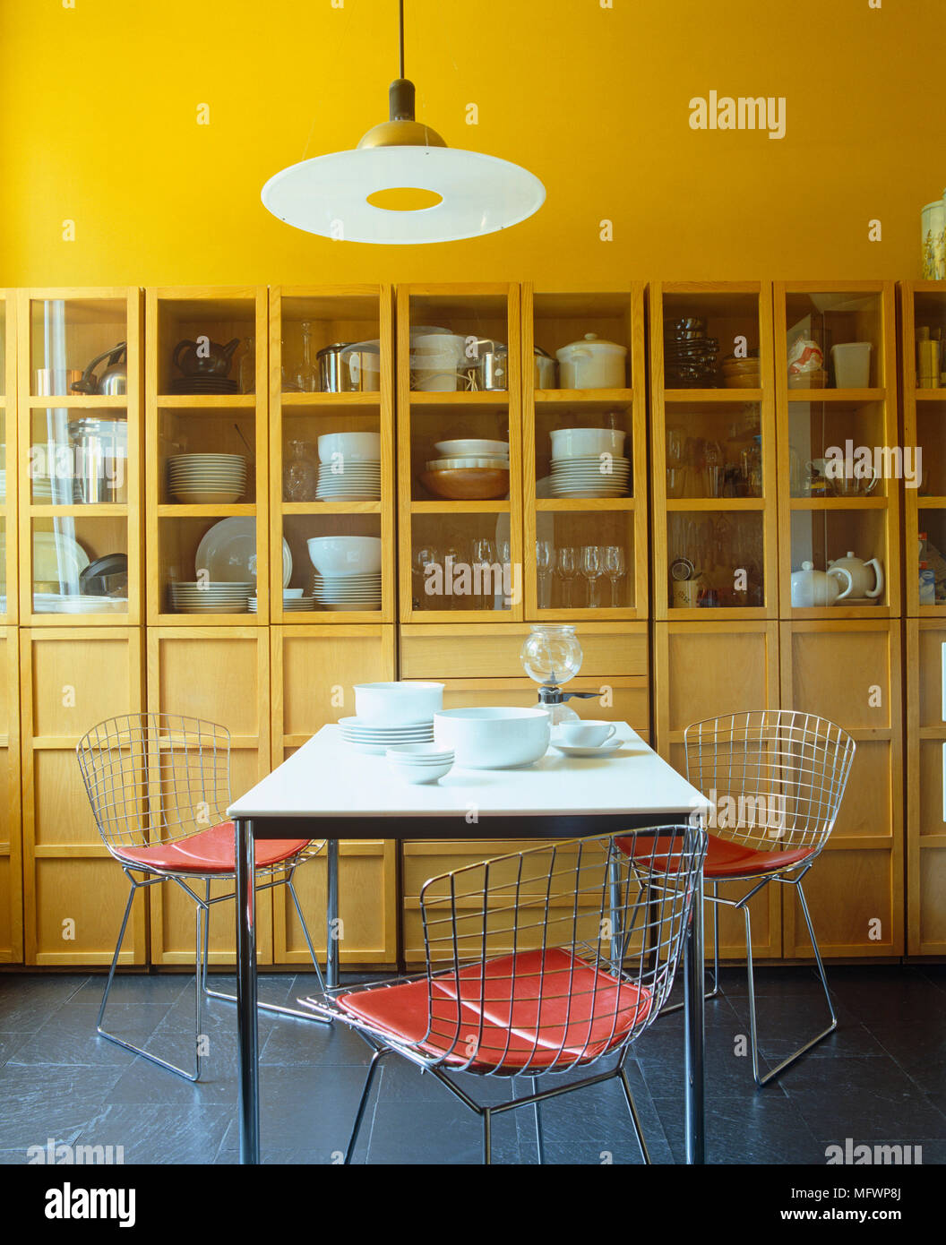 Harry Bertoia wire chairs at table in contemporary yellow dining room Stock Photo