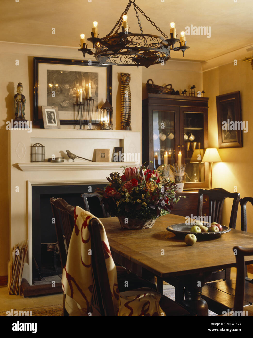 Wrought Iron Chandelier Suspended Above Wooden Table And Chairs In Front Of Fireplace Wrought Iron Chandelier Suspended Above Wooden Table And Chairs In Front Of Fireplace