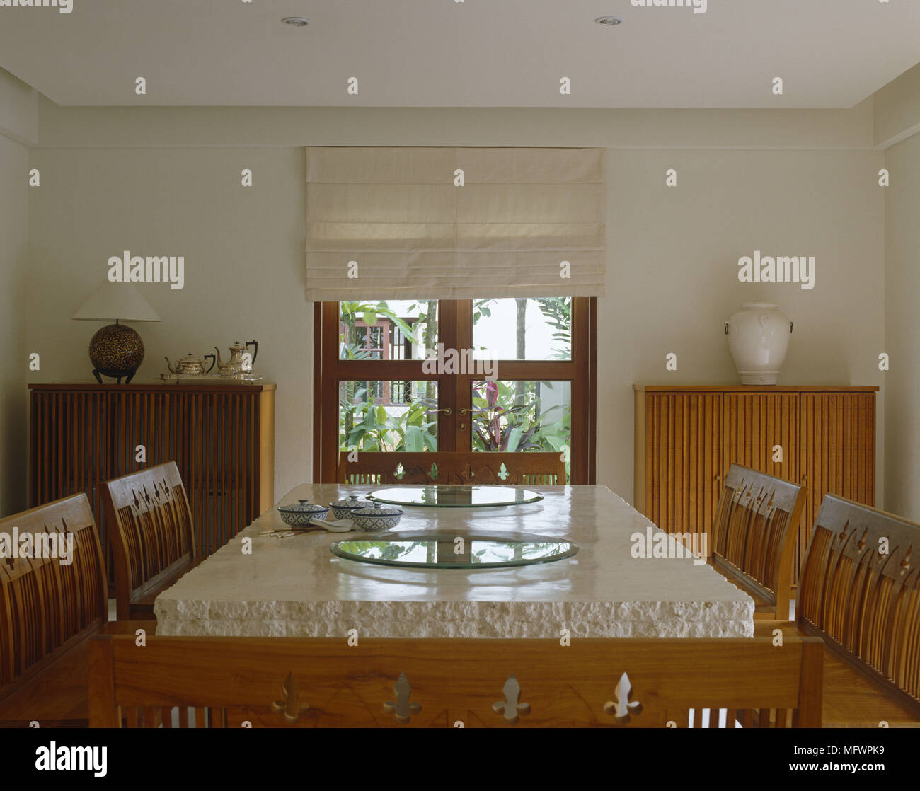 Wooden seats around a dining table with heavy stone top in front of