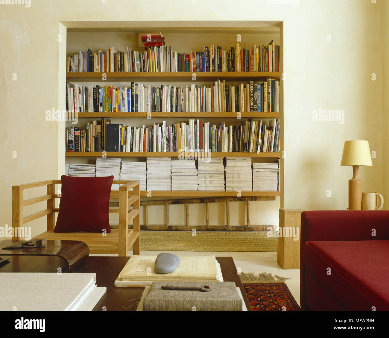 Bookshelf Unit Set Into Wall Behind Armchair With Red Cushion And