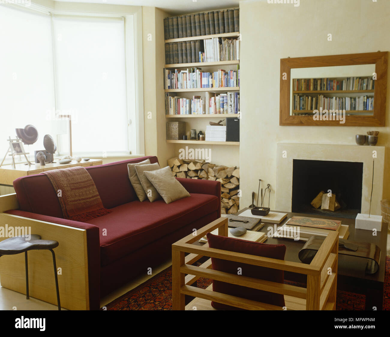 Wooden framed red sofa facing coffee table in front of fireplace
