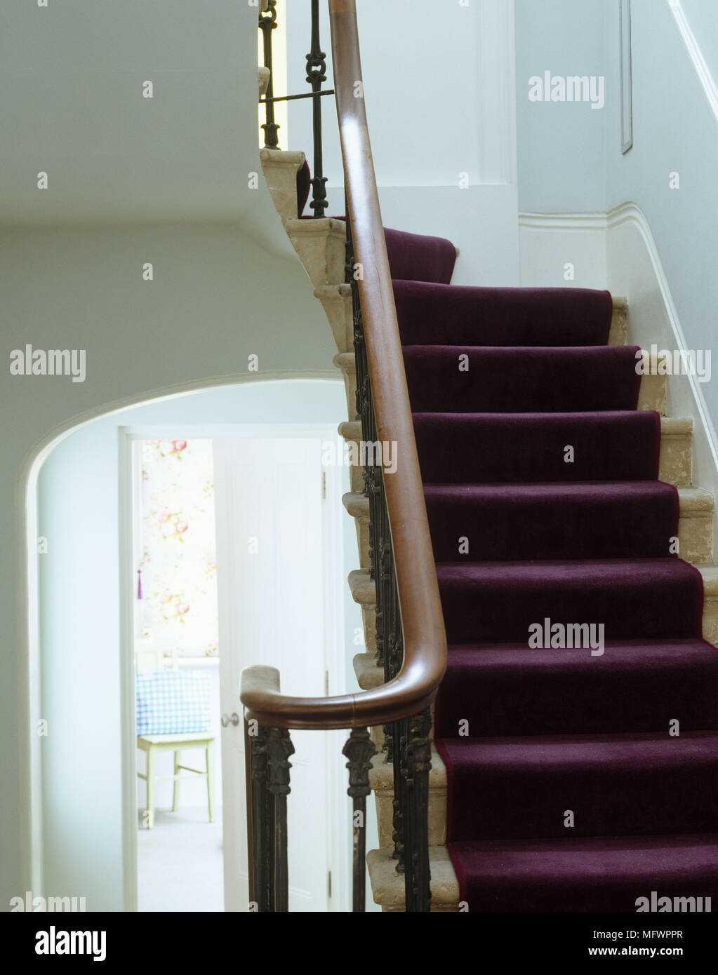 Traditional style staircase with purple carpet and wooden banister ...