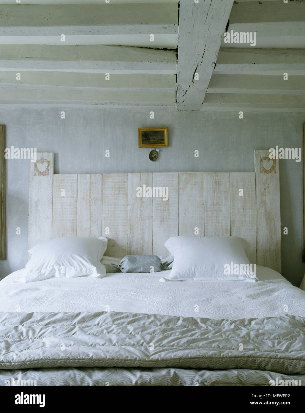 Rustic bedroom with double bed with white linen and wooden headboard