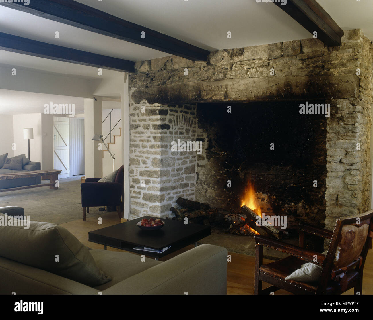 Rustic fireplace in room with exposed beams and sofa facing coffee