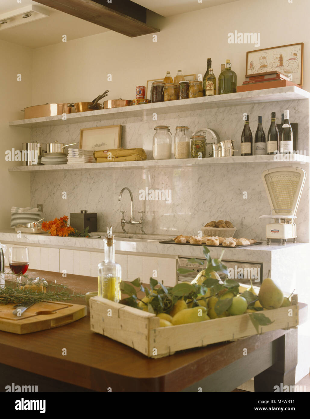 Kitchen with fresh fruit on wooden table in front of marble unit