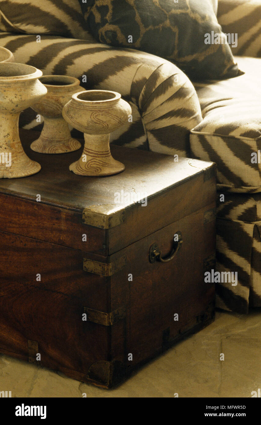 Ornamental vases on dark wood chest next to armchair Stock Photo