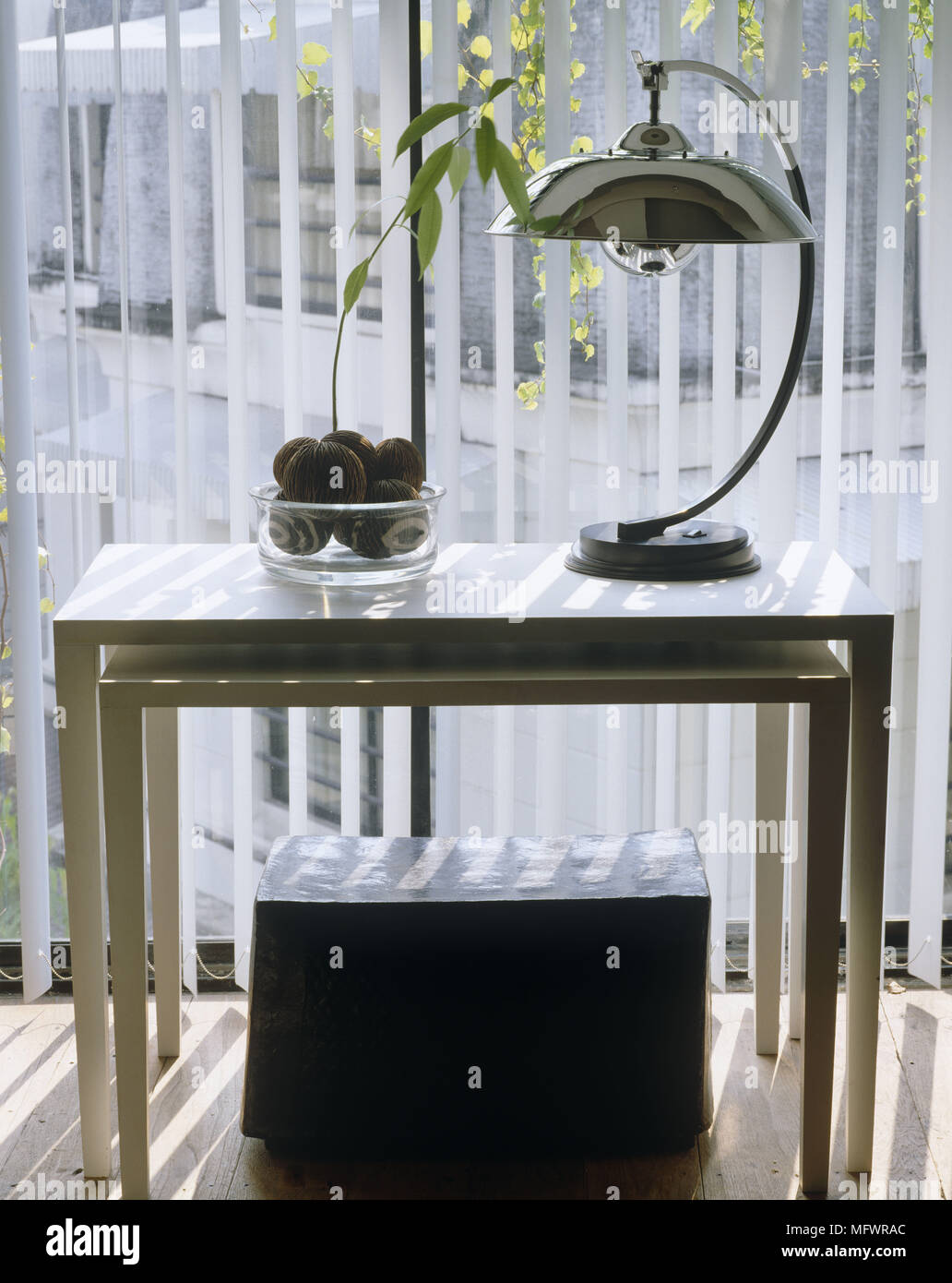 Ornaments And Silver Lamp On Nest Of Tables In Front Of Window