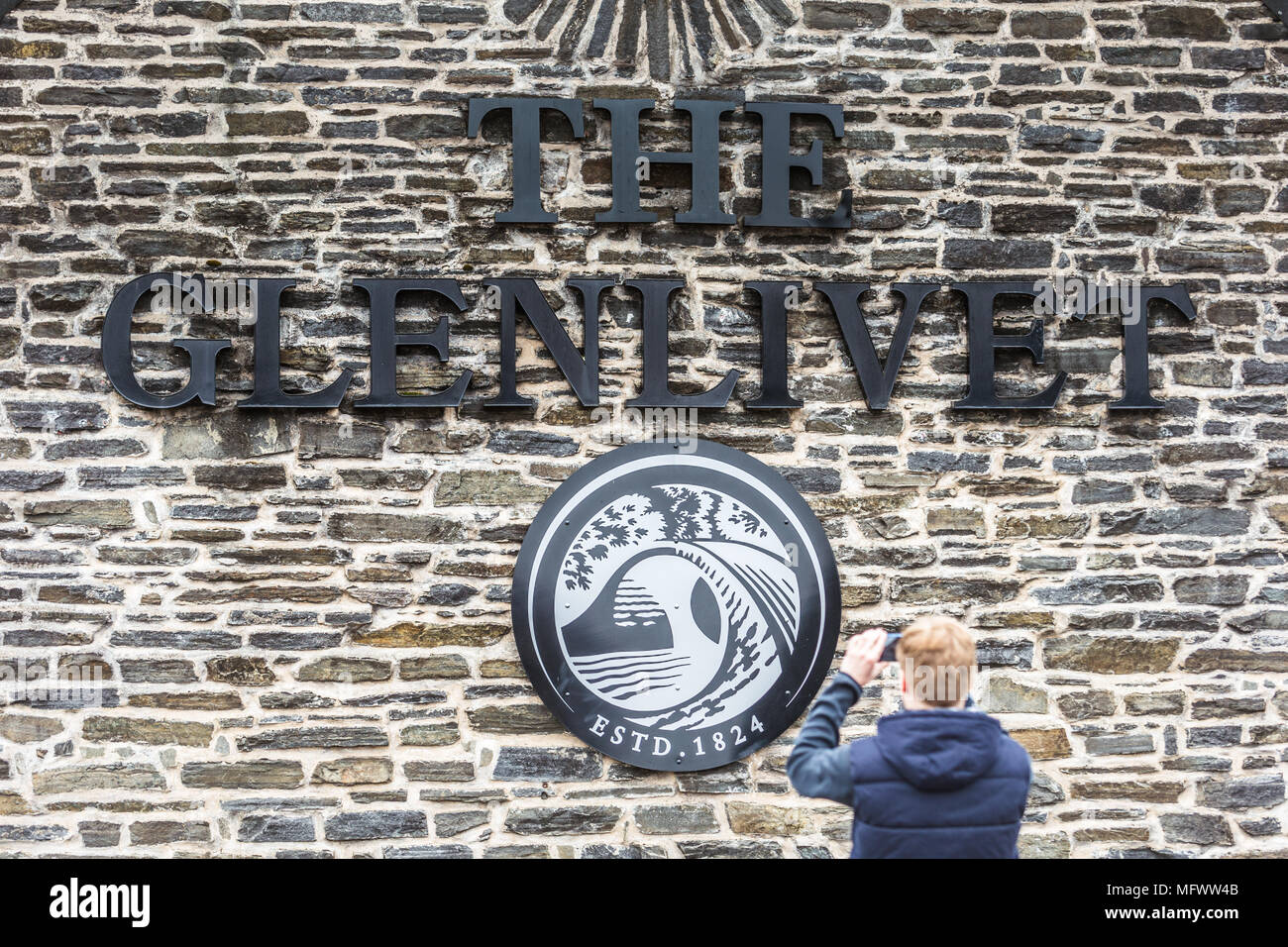 Aman visitor takes a mobilephone photograph outside the Glenlivet whisky distillery Scotland UK Stock Photo