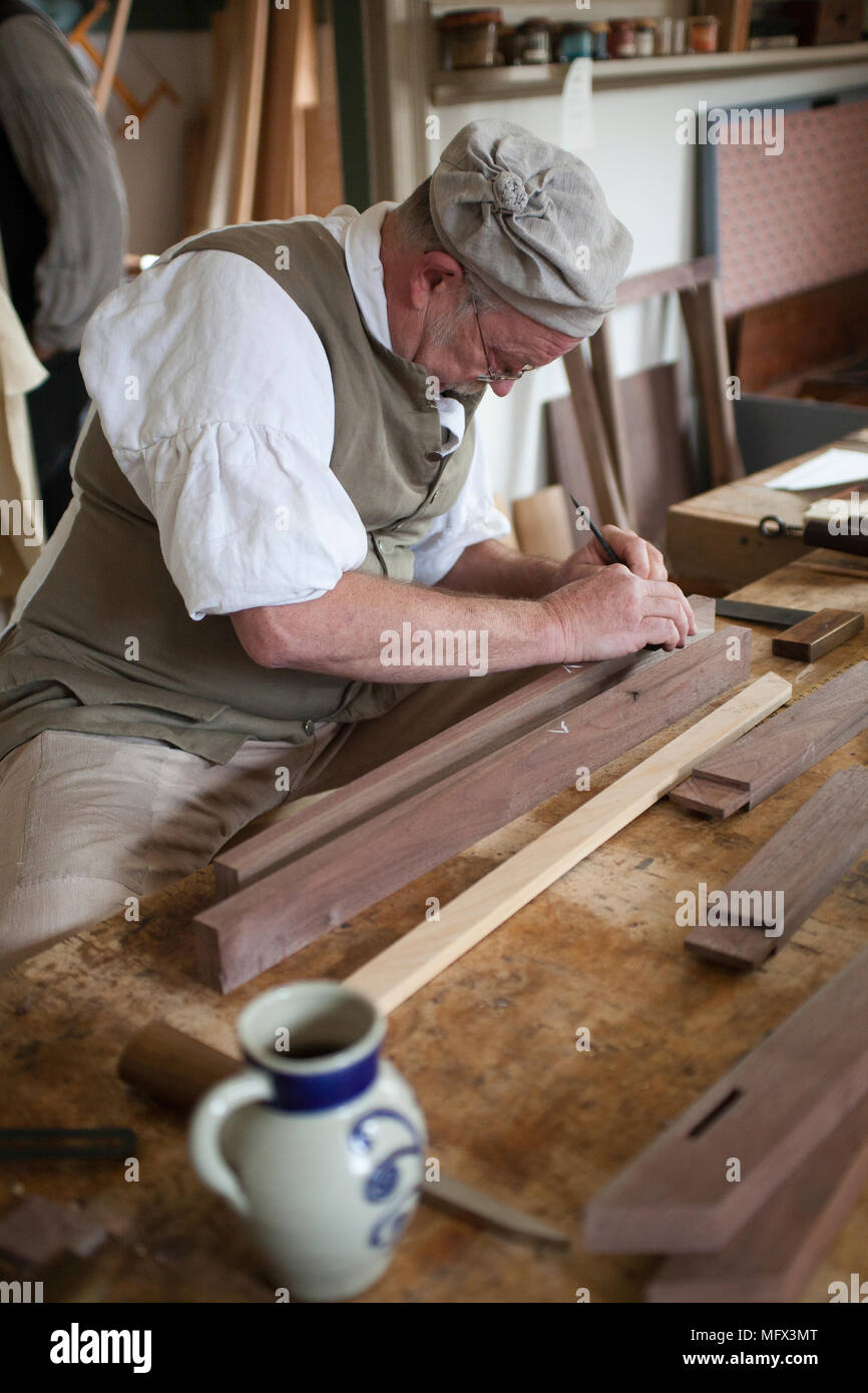 Cabinet maker in authentic early American clothing working in his shop surrounded by his authentic tools in colonial Williamsburg Virginia Stock Photo