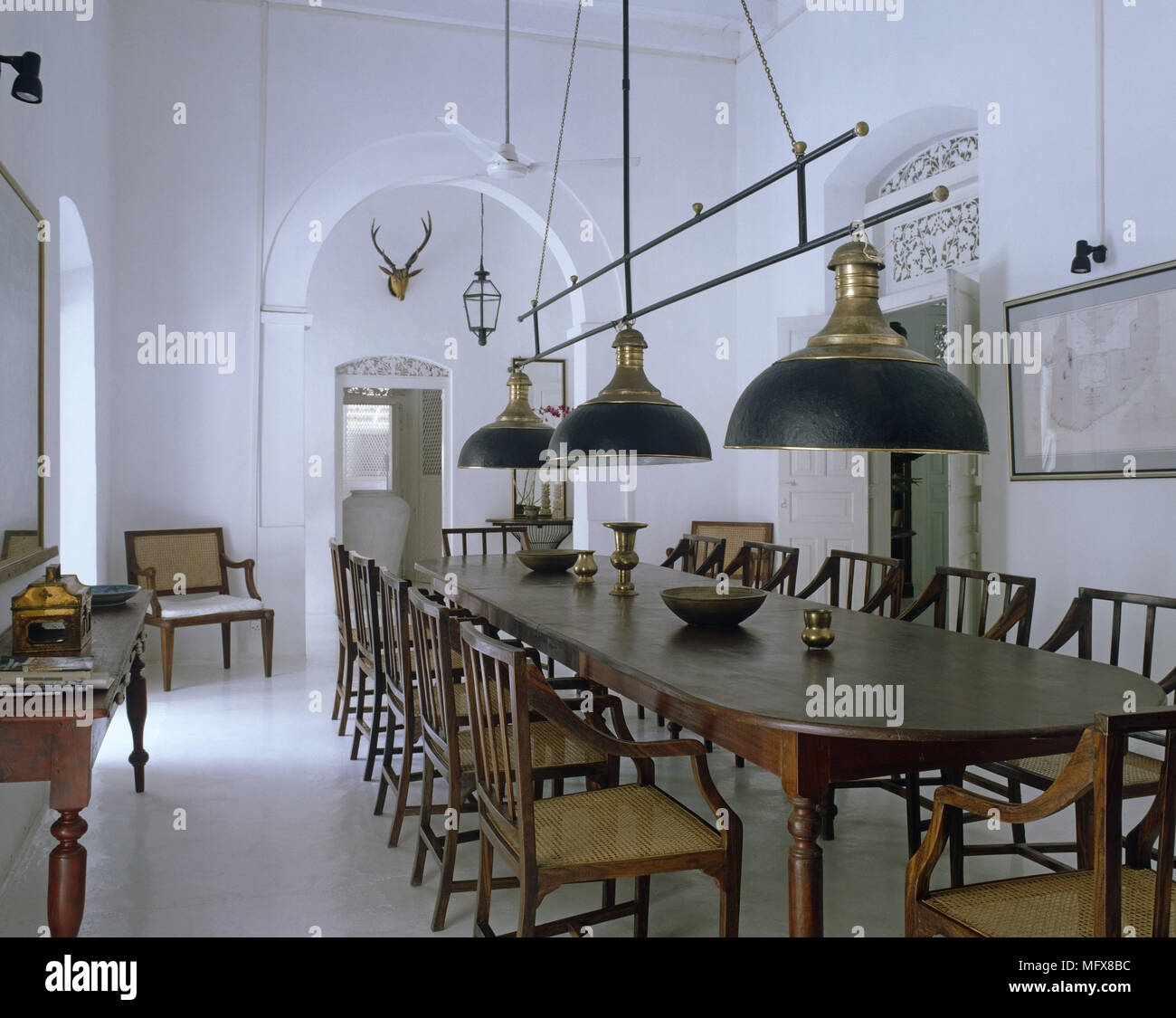 Ceiling Lights Suspended Over Wooden Table And Chairs In Spacious Dining Room Stock Photo Alamy
